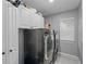 Well-equipped laundry room with modern gray washer and dryer, complemented by white cabinets for storage at 15618 Shoal Creek Pl, Odessa, FL 33556