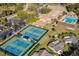 Aerial view of the community showcasing tennis courts, a pool, a clubhouse, and lush landscaping at 2958 Macalpin N Dr, Palm Harbor, FL 34684