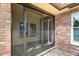 Covered front entry with brick accents, a screened storm door, and access to the front door at 2958 Macalpin N Dr, Palm Harbor, FL 34684