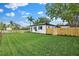Spacious backyard featuring a well-maintained lawn, a secure fence, and a charming white home at 3520 Poplar Ne St, St Petersburg, FL 33704