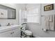 Bright bathroom featuring a white sink vanity, toilet, and matching storage cabinet, and decorative artwork at 3822 W Euclid Ave, Tampa, FL 33629