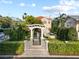 A pergola-covered gate leads to a meticulously landscaped backyard with a water feature and lush greenery at 608 Orange Ave, Clearwater, FL 33756