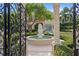 View through iron gate to garden with fountain, manicured hedges, and Mediterranean-style home at 608 Orange Ave, Clearwater, FL 33756