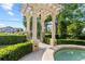 Backyard pergola with columns, fountain, manicured hedges, and a gated entrance at 608 Orange Ave, Clearwater, FL 33756