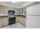 Compact kitchen featuring a white refrigerator, tile backsplash, and dark appliances at 6826 Stones Throw N Cir # 11104, St Petersburg, FL 33710
