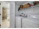 Laundry room with full size washer and dryer, and storage shelves, adjacent to bathroom at 6826 Stones Throw N Cir # 11104, St Petersburg, FL 33710
