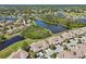 An aerial view exhibits a home within a neighborhood, nearby lush greenery, and pond at 767 Tremont Greens Ln # 64, Sun City Center, FL 33573