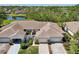 Aerial view of a well-maintained villa with a two car garage near a serene pond and lush greenery at 767 Tremont Greens Ln # 64, Sun City Center, FL 33573