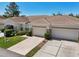 Condo featuring a two-car garage, manicured lawn, and walkway at 767 Tremont Greens Ln # 64, Sun City Center, FL 33573