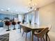 Bright dining room features tiled floor, slider to balcony, a modern chandelier, and view of the kitchen at 10240 Bayou Grande Ave, Seminole, FL 33772