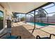 View of the screened-in pool area with brick pavers, outdoor seating, and lush landscaping at 13524 91St Ave, Seminole, FL 33776