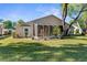 Back exterior with an enclosed patio featuring potted plants and landscaping at 13526 Norman Cir, Hudson, FL 34669