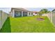 Large backyard with lush green grass and a view of the screened-in lanai and well-maintained fence at 17152 Scuba Crest St, Wimauma, FL 33598