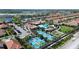 This aerial view shows a community with mature landscaping, a pool, tennis courts and water features at 17418 Holly Well Ave, Wimauma, FL 33598