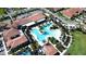 An aerial view of a community center pool surrounded by tropical landscaping with a sunbathing patio and ample seating at 17418 Holly Well Ave, Wimauma, FL 33598