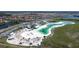 This aerial view shows a beach-themed amenity center with a large sand beach, sun bathing chairs, and a pristine aqua-colored lagoon at 17418 Holly Well Ave, Wimauma, FL 33598