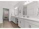 Bright bathroom with double sinks, stylish mirrors, and ample counter space with access to walk-in closet at 17418 Holly Well Ave, Wimauma, FL 33598