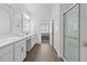 Bright bathroom featuring double vanity, wood-look tile flooring, and a glass-enclosed shower at 17418 Holly Well Ave, Wimauma, FL 33598