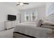 Comfortable main bedroom boasts a plush queen bed, a television, and plenty of natural light at 17418 Holly Well Ave, Wimauma, FL 33598