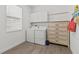 Functional laundry room with side-by-side washer and dryer, storage cabinets and tiled flooring at 17418 Holly Well Ave, Wimauma, FL 33598