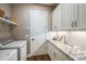 Functional laundry room with a washer, dryer, granite countertops, and ample storage space at 17716 Roost Pl, Lakewood Ranch, FL 34211
