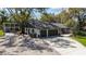 Home's two-car garage, featuring a gravel drive and mature trees for ample shade at 2085 Lynnwood Ct, Dunedin, FL 34698