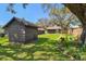 Backyard view featuring dark-stained shed, green lawn, and flower bed with pinwheel decorations at 3010 County Road 31, Clearwater, FL 33759