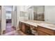 Bathroom featuring a double vanity, large mirror, a walk-in shower with brown tile and a view into the bedroom at 31820 Blythewood Way, Wesley Chapel, FL 33543