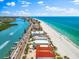 An aerial view features beachfront houses alongside a road, with docks, a beautiful beach, and clear blue water at 32 Gulf Blvd, Indian Rocks Beach, FL 33785