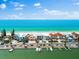 An aerial view features beachfront houses alongside a road, with docks, a beautiful beach, and clear blue water at 32 Gulf Blvd, Indian Rocks Beach, FL 33785
