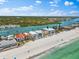 An aerial view features beachfront houses alongside a road, with docks, a beautiful beach, and clear blue water at 32 Gulf Blvd, Indian Rocks Beach, FL 33785