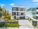 Modern three-story home with gray and white exterior, balconies, manicured landscaping, and paver driveway at 32 Gulf Blvd, Indian Rocks Beach, FL 33785