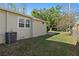 View of a grassy backyard, including a beige house, air conditioning unit, and a partial view of a chainlink fence at 3220 10Th N St, St Petersburg, FL 33704