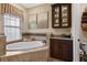 A relaxing bathroom featuring a large soaking tub and custom cabinets at 3543 Watermark Dr, Wesley Chapel, FL 33544