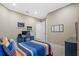 Bright bedroom with a blue, orange and white striped bed, neutral walls, carpeted floors, and a gaming-themed desk area at 3543 Watermark Dr, Wesley Chapel, FL 33544