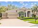 Attractive home exterior with a brick driveway, three-car garage, and lush landscaping at 3543 Watermark Dr, Wesley Chapel, FL 33544