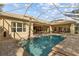 Screened-in pool with a spa, brick patio, outdoor seating, and view of the home and landscaped yard at 3543 Watermark Dr, Wesley Chapel, FL 33544