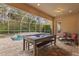 Screened-in pool and hot tub with a pool table, outdoor seating, and view of the lush greenery at 3543 Watermark Dr, Wesley Chapel, FL 33544