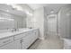 Bright bathroom with double vanity, modern lighting, and glass enclosed shower and separate toilet area at 4597 Blue Star Ct, North Port, FL 34289