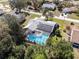 Aerial view of a screened-in pool surrounded by solar panels and lush greenery in a residential neighborhood at 5232 Kirkwood Ave, Spring Hill, FL 34608