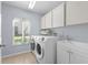 Bright laundry room features updated washer and dryer, ample cabinet space, and a window bringing in natural light at 5232 Kirkwood Ave, Spring Hill, FL 34608