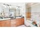 Bathroom featuring double sinks with wood cabinets, a soaking tub, and mirrors with vanity lighting at 700 N Osceola Ave # 504, Clearwater, FL 33755