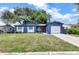 Charming blue single-story home featuring a red door, white garage door and shutter accents, and a well-maintained lawn at 11791 128Th Ave, Largo, FL 33778