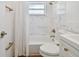 Bathroom featuring modern gold fixtures, marble-tiled walls, and a shower-tub combo with a white curtain at 1260 S Hillcrest Ave, Clearwater, FL 33756