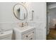 Modern bathroom featuring a round mirror with gold trim, marble walls and countertops with gold fixtures at 1260 S Hillcrest Ave, Clearwater, FL 33756