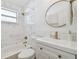 Beautiful bathroom featuring marble tiled walls, a stylish round mirror, and modern gold fixtures at 1260 S Hillcrest Ave, Clearwater, FL 33756