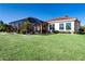 Sprawling backyard featuring lush green lawn and a screened-in lanai with mature tropical landscaping at 1308 Crystal Greens Dr, Sun City Center, FL 33573