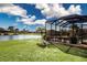Expansive backyard featuring a pond, a screened lanai, lush landscaping, and well-manicured lawn at 1308 Crystal Greens Dr, Sun City Center, FL 33573