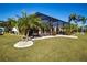 Backyard featuring a pool and screened lanai, tropical landscaping, lush green lawn, and white stone accents at 1308 Crystal Greens Dr, Sun City Center, FL 33573