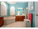 Bright bathroom with tile floors, vanity, soaking tub under arch window, and turquoise walls at 1308 Crystal Greens Dr, Sun City Center, FL 33573